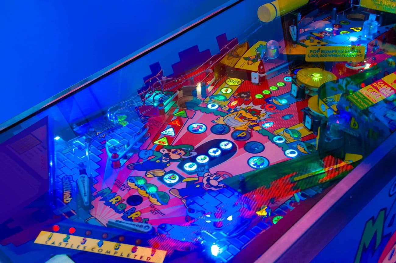 Close-up of an illuminated pinball machine playfield lit in blue.
