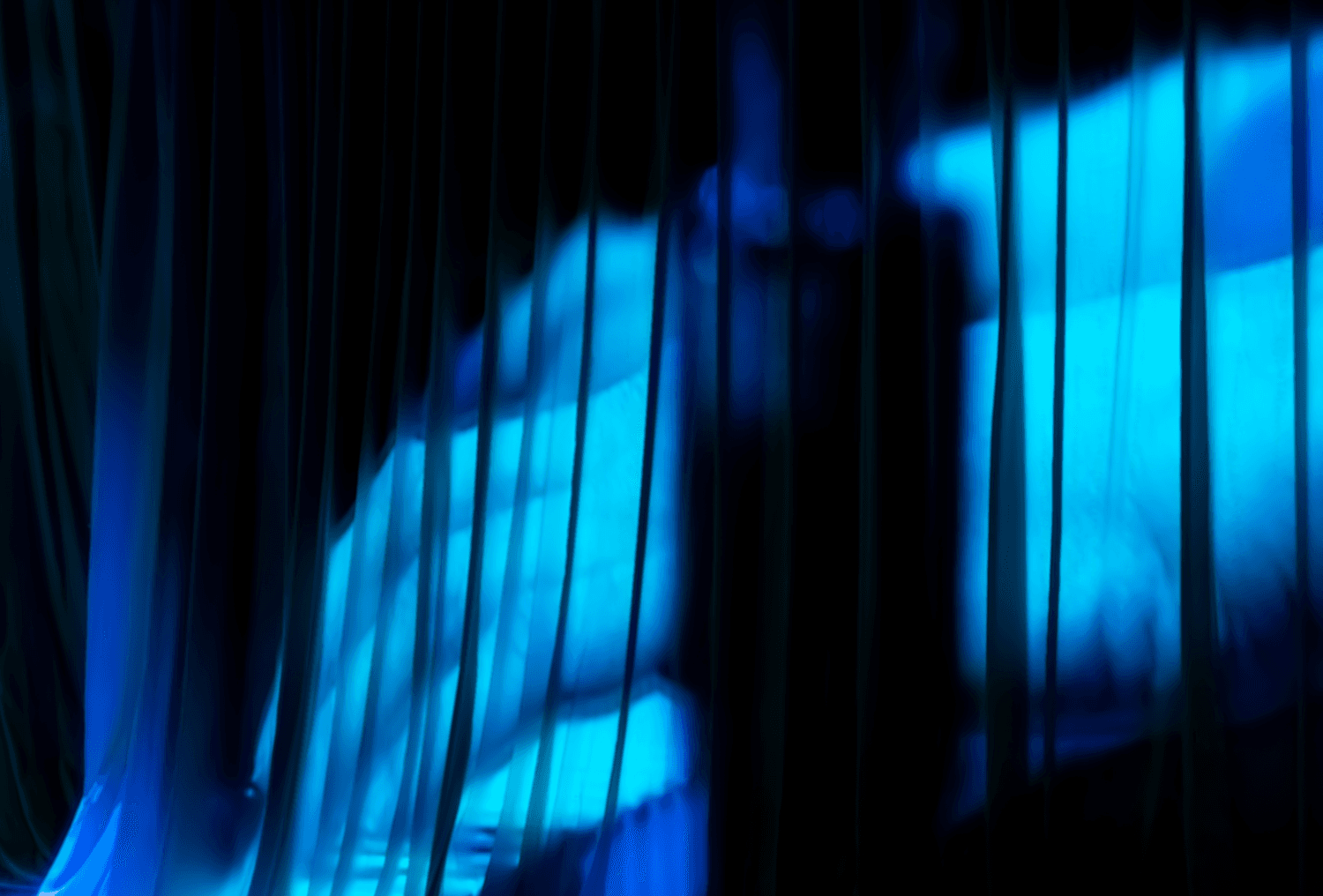Blue-lit draped curtain panels creating a wave-like pattern on stage