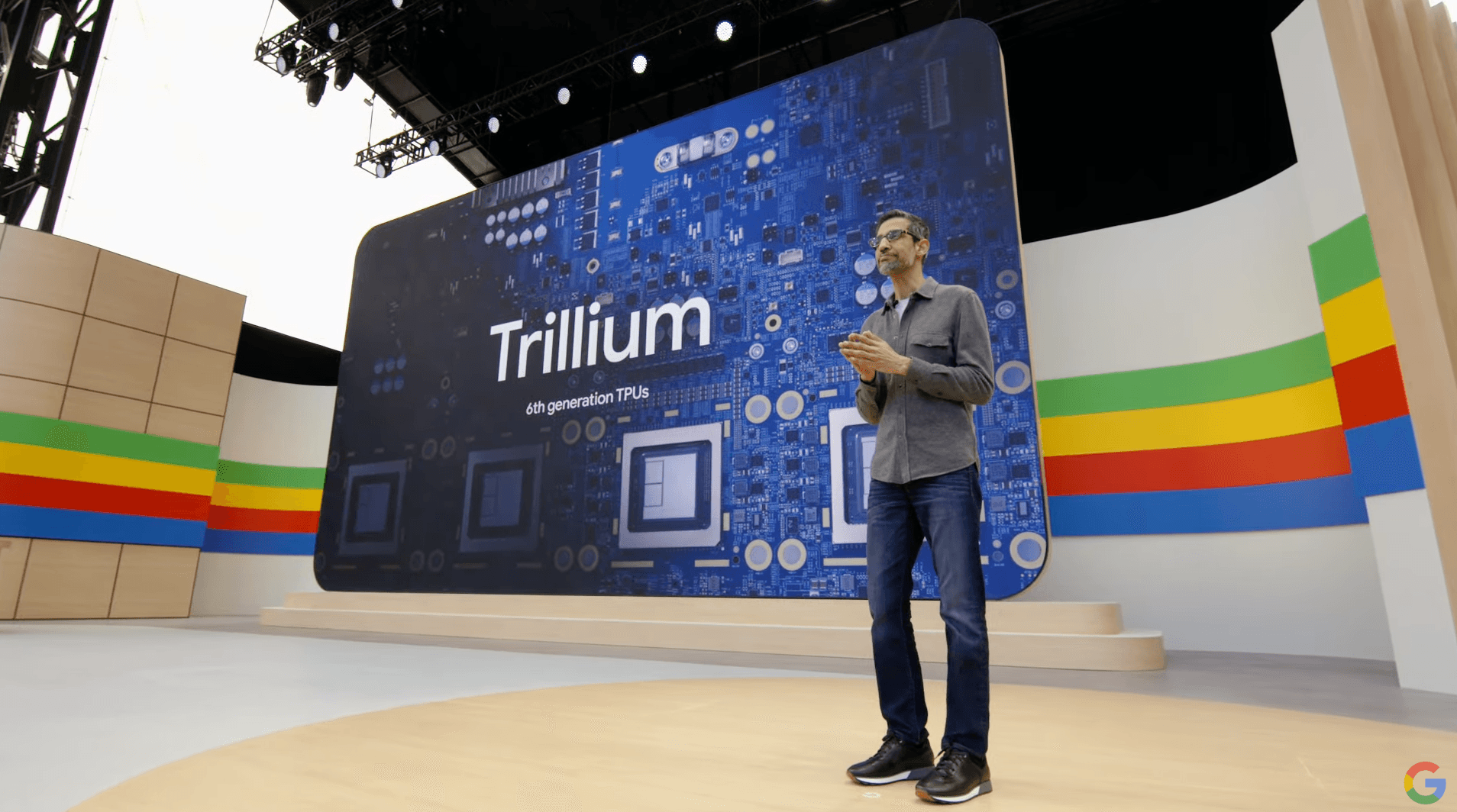 Presenter beside a large screen reading 'Trillium' with a circuit board graphic, on the I/O stage set.
