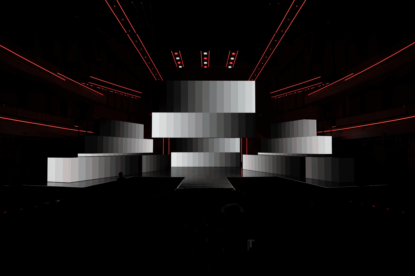 Cluster of angled silver panels lit against a dark stage backdrop