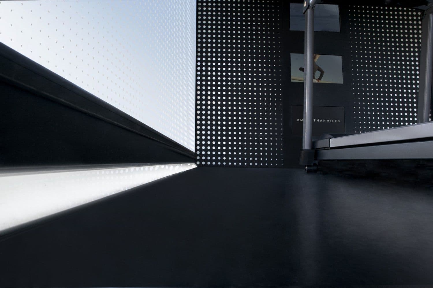 Architectural detail of an illuminated ramp threshold beside perforated dot-pattern wall panels