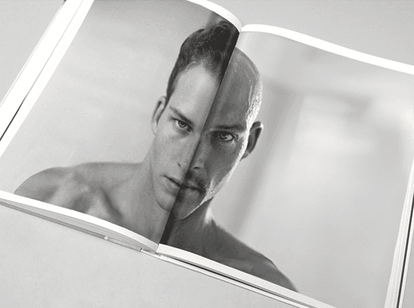 Book spread with a split black-and-white portrait of a shirtless man's face divided into two contrasting halves.