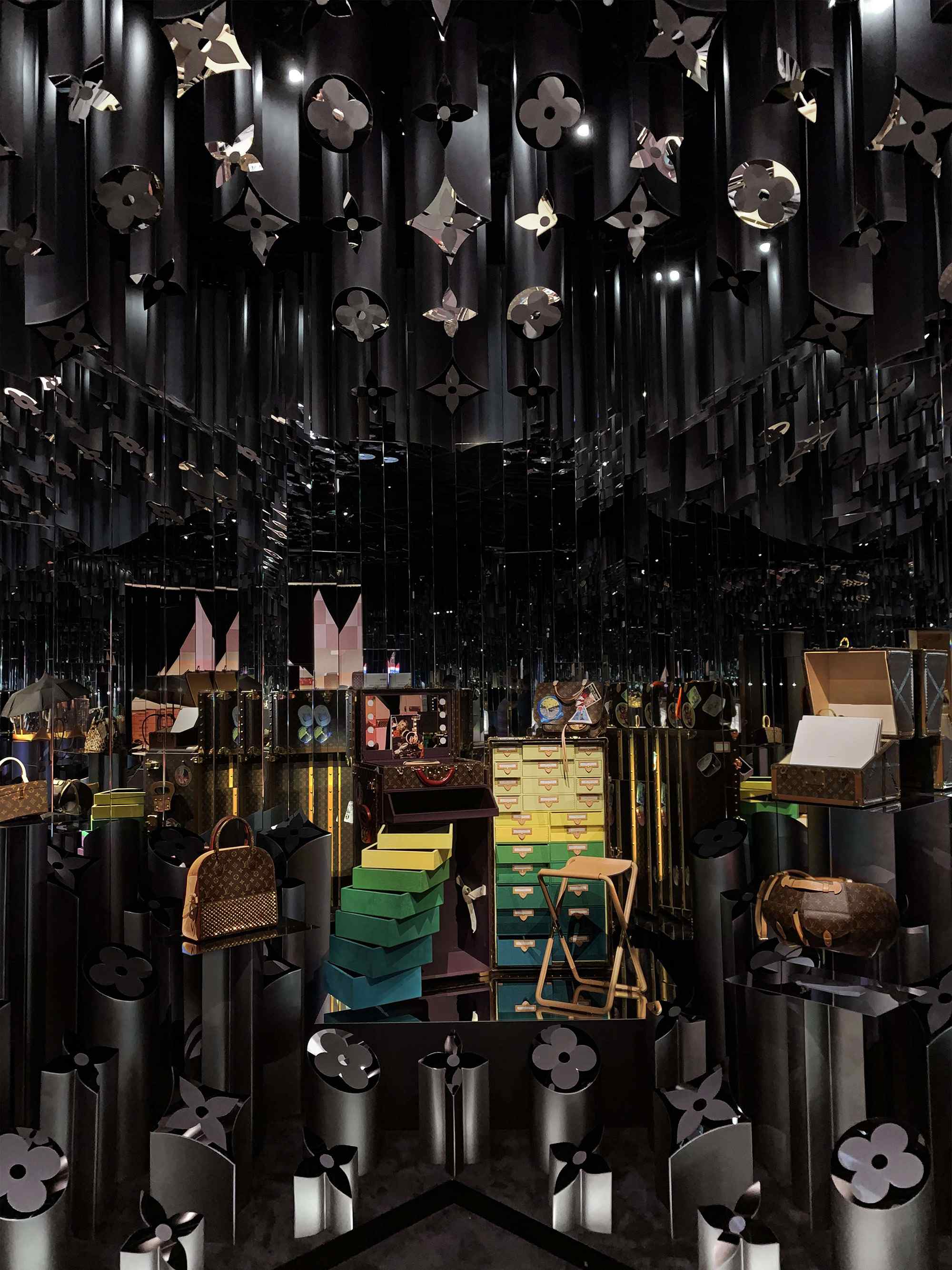 Dark installation with black charms hanging from the ceiling above a table of small display items.