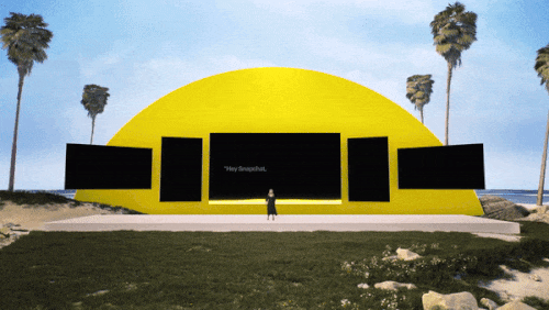 Sunset over a desert stage set with yellow panels and photo cutouts of people.