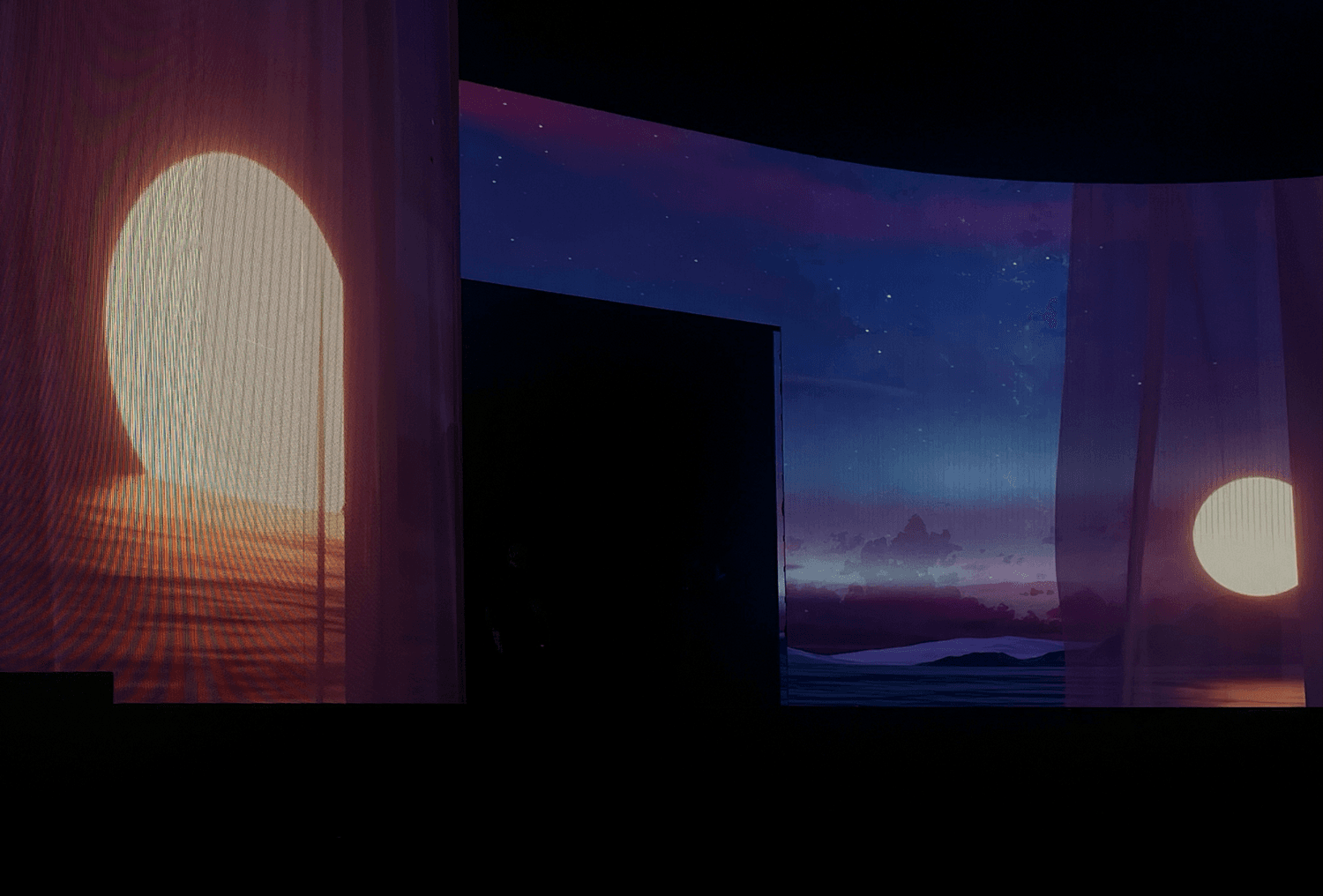 Glowing archway lit against a dark stage with a projected moon or sun
