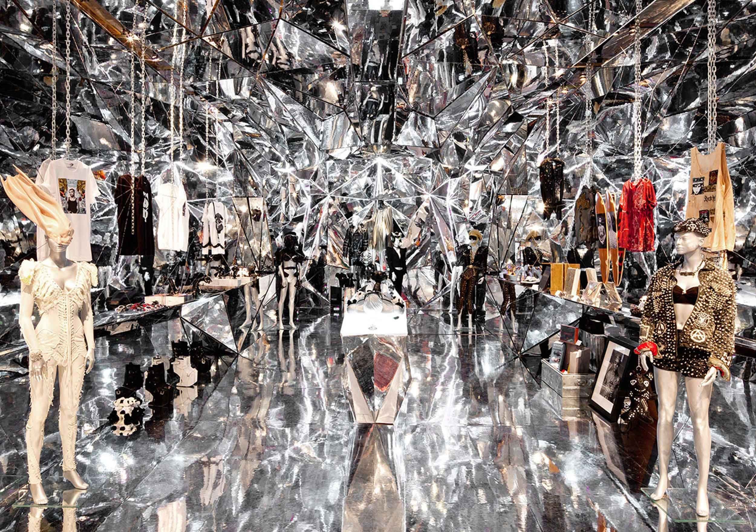 Store installation with mirrored disco balls hanging above mannequins and clothing racks.