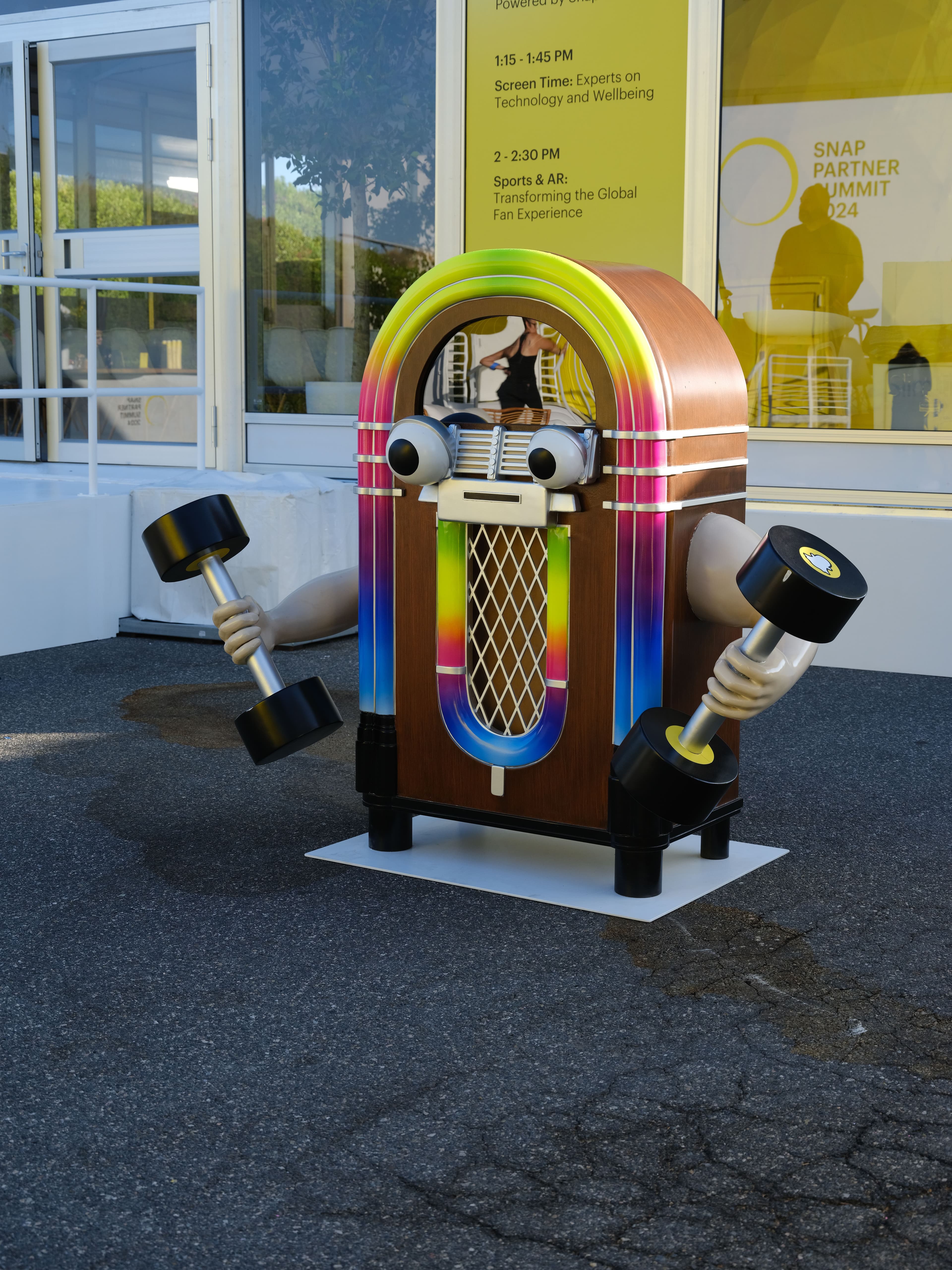 Colorful jukebox-style kiosk with speaker horns, displayed outside a building.