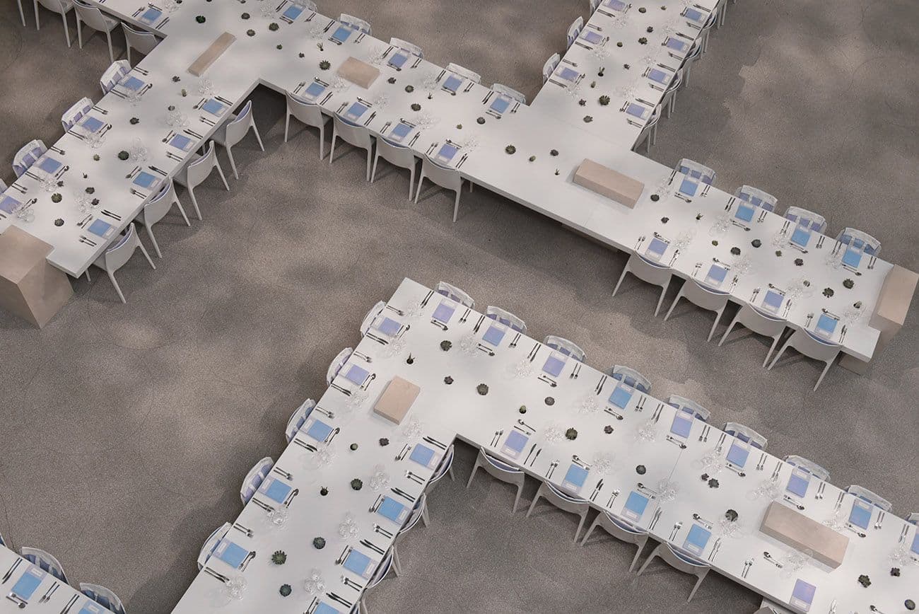 Aerial view of two cross-shaped dinner table arrangements with chairs set around them