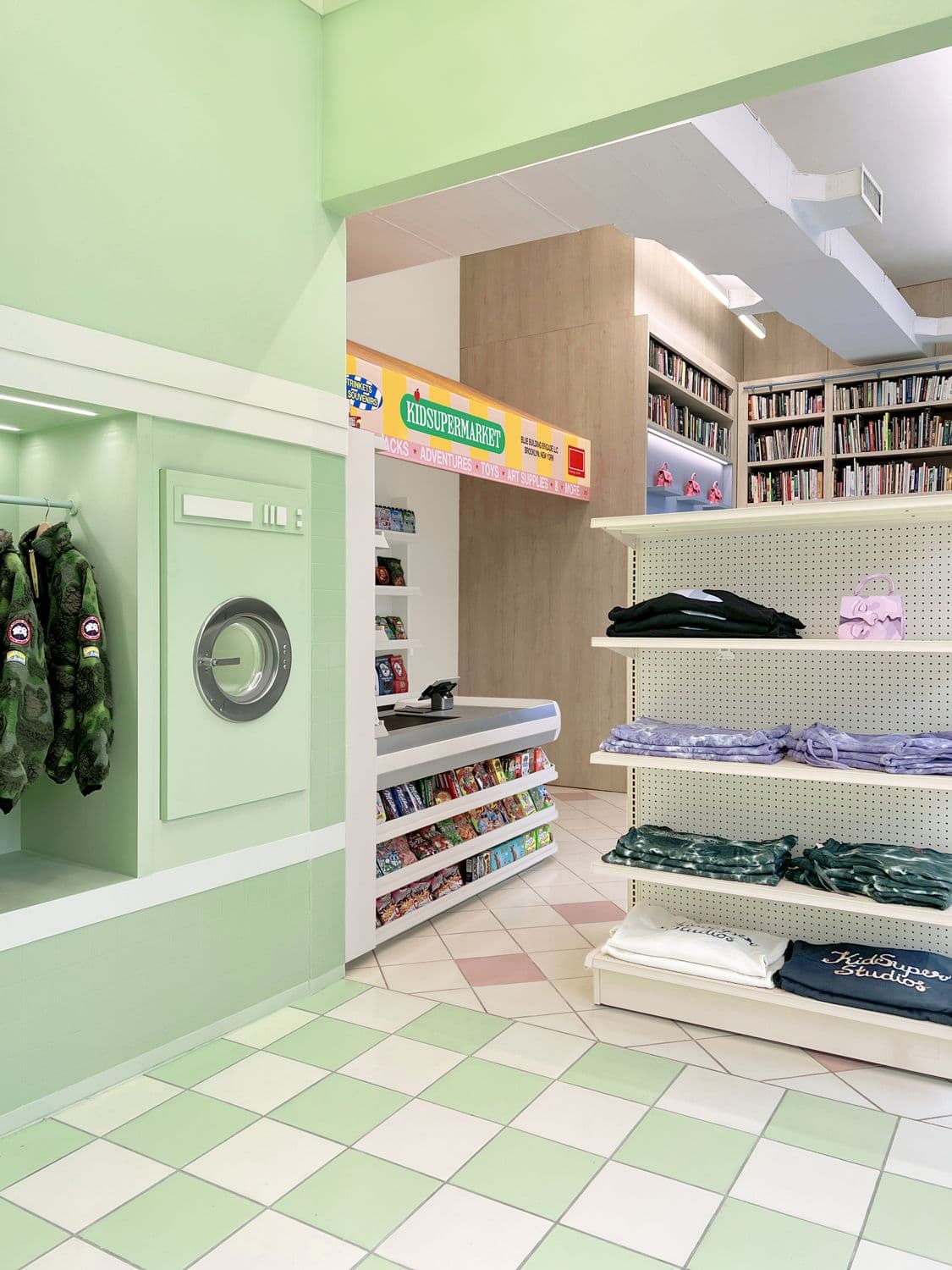 Mint-green retail store interior with a washing machine display unit, open shelving, and folded merchandise
