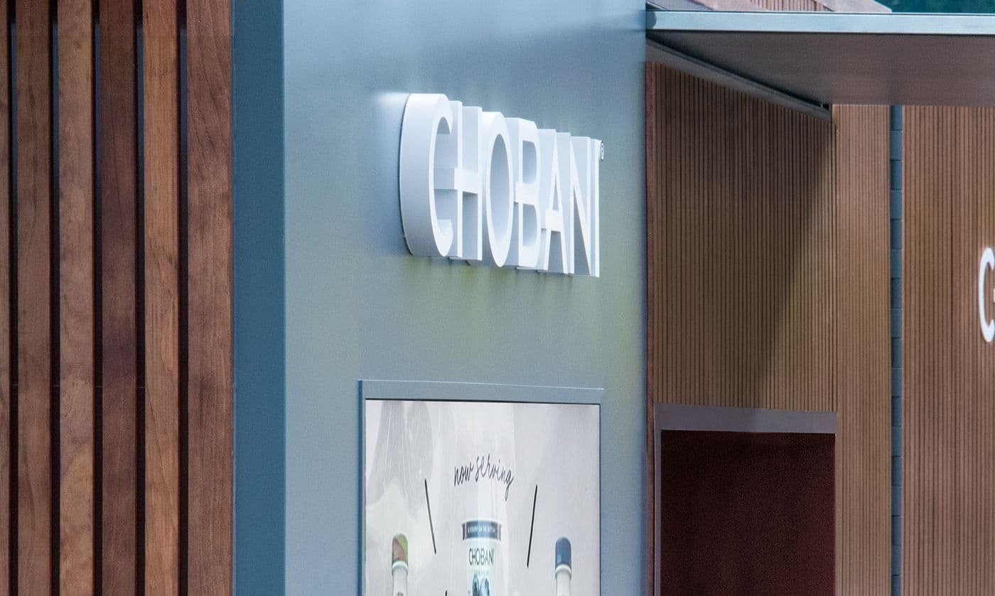 Close-up of the trailer's teal end panel with CHOBANI lettering and a small product photo, wood slats behind.