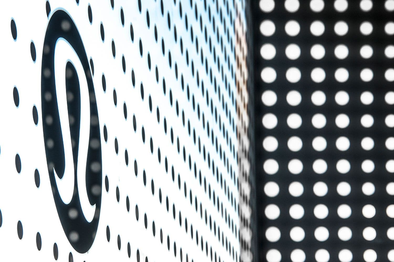 Close-up of the dotted lululemon logo wall panel beside a solid dot-pattern screen