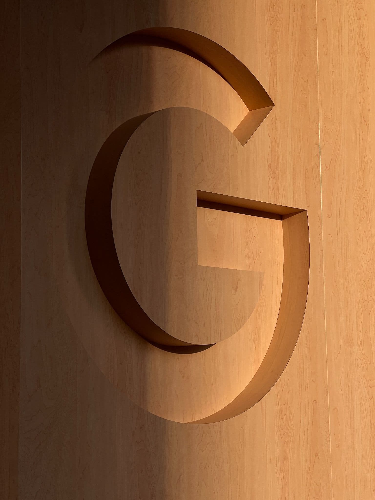 Close-up of a wooden 'G' letterform carved into a stage wall panel.