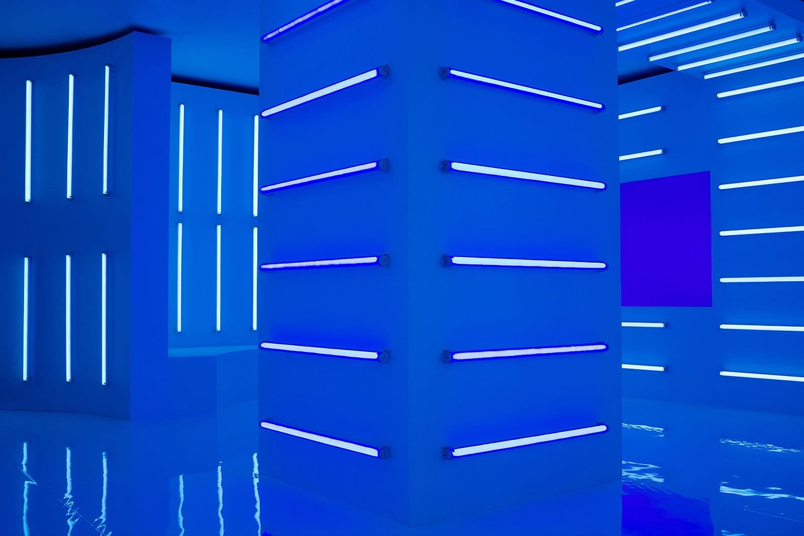 Electric-blue room with angled walls striped in white neon light bars.