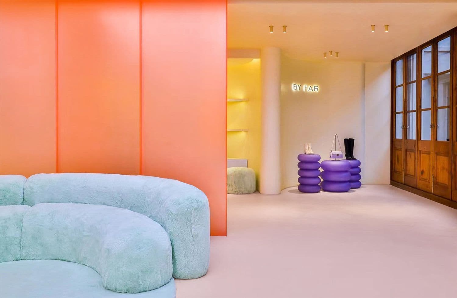 Orange hallway leading to a framed artwork, with pink seating visible through an archway