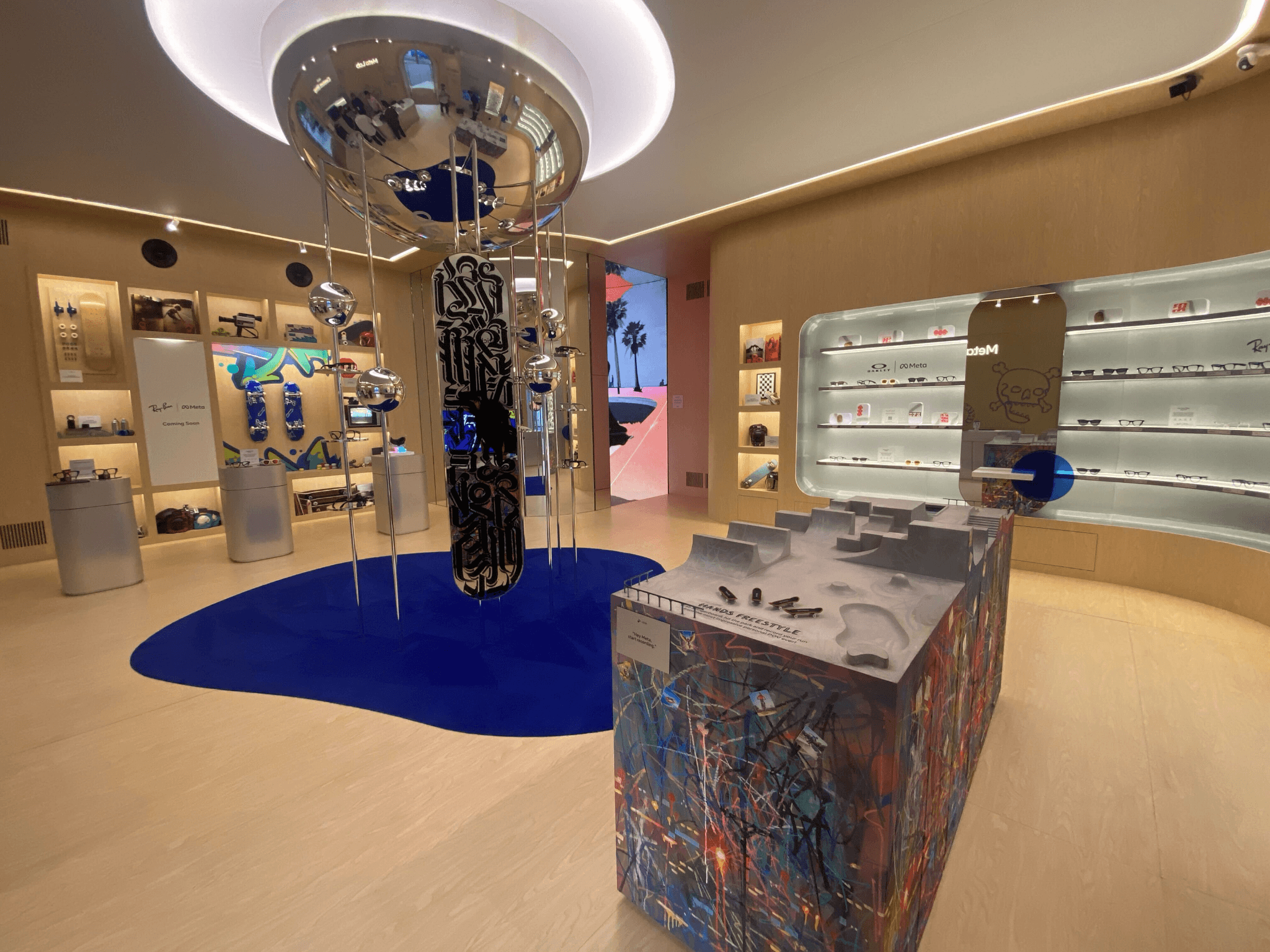 Showroom interior with a circular ceiling display, glass cases of glasses, and a sculptural pedestal on a blue rug.