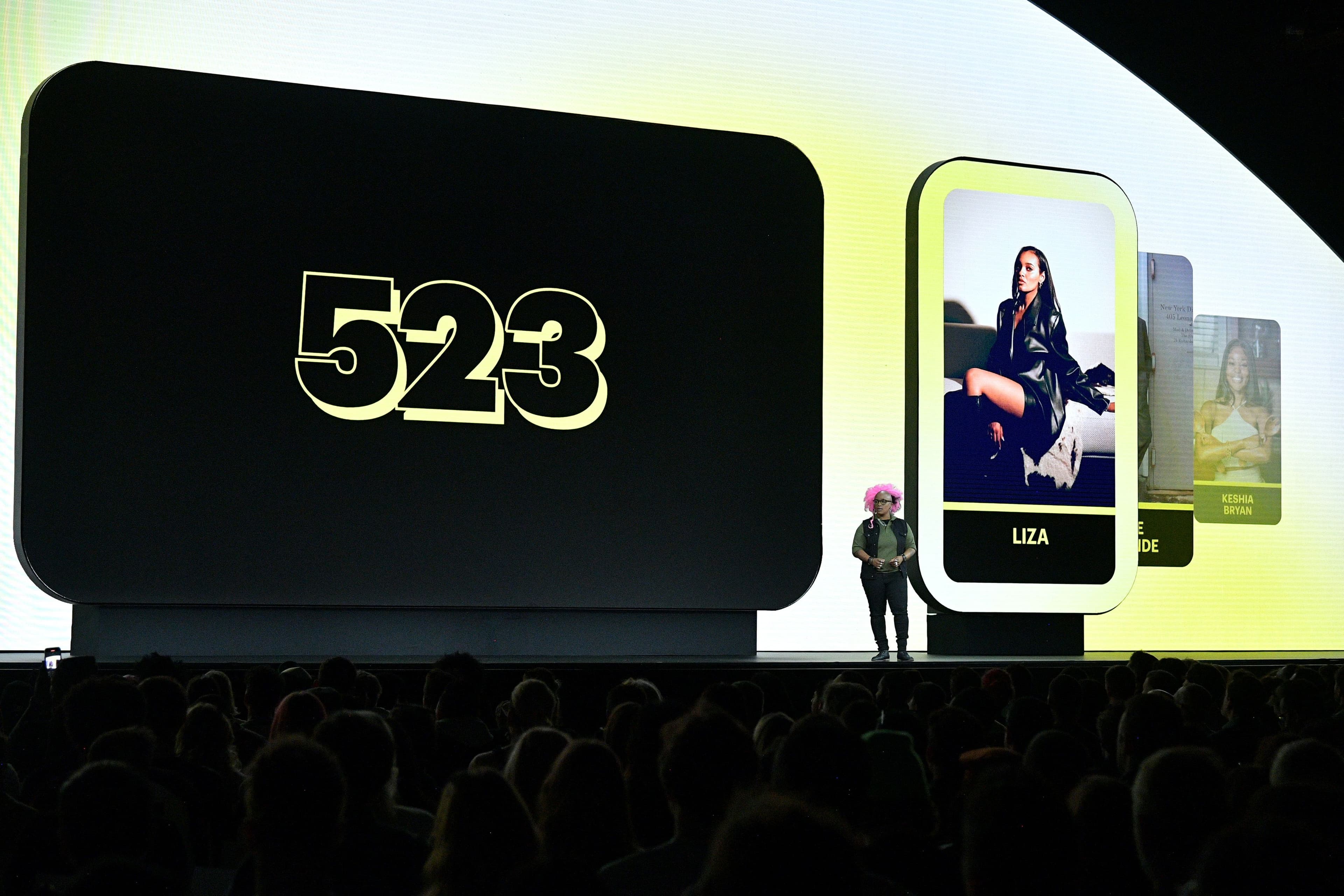 Stage screen displaying the number 523 beside a phone graphic, audience seated below.