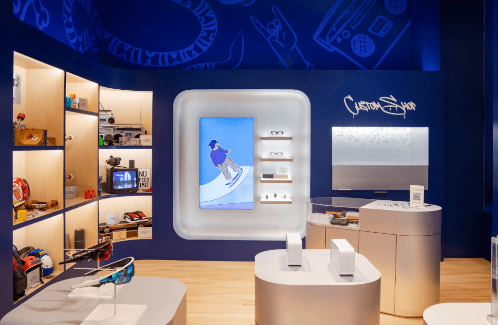 Blue-walled shop interior with illustrated line art on the walls, wall shelving of products, and a rounded white display counter with screen.