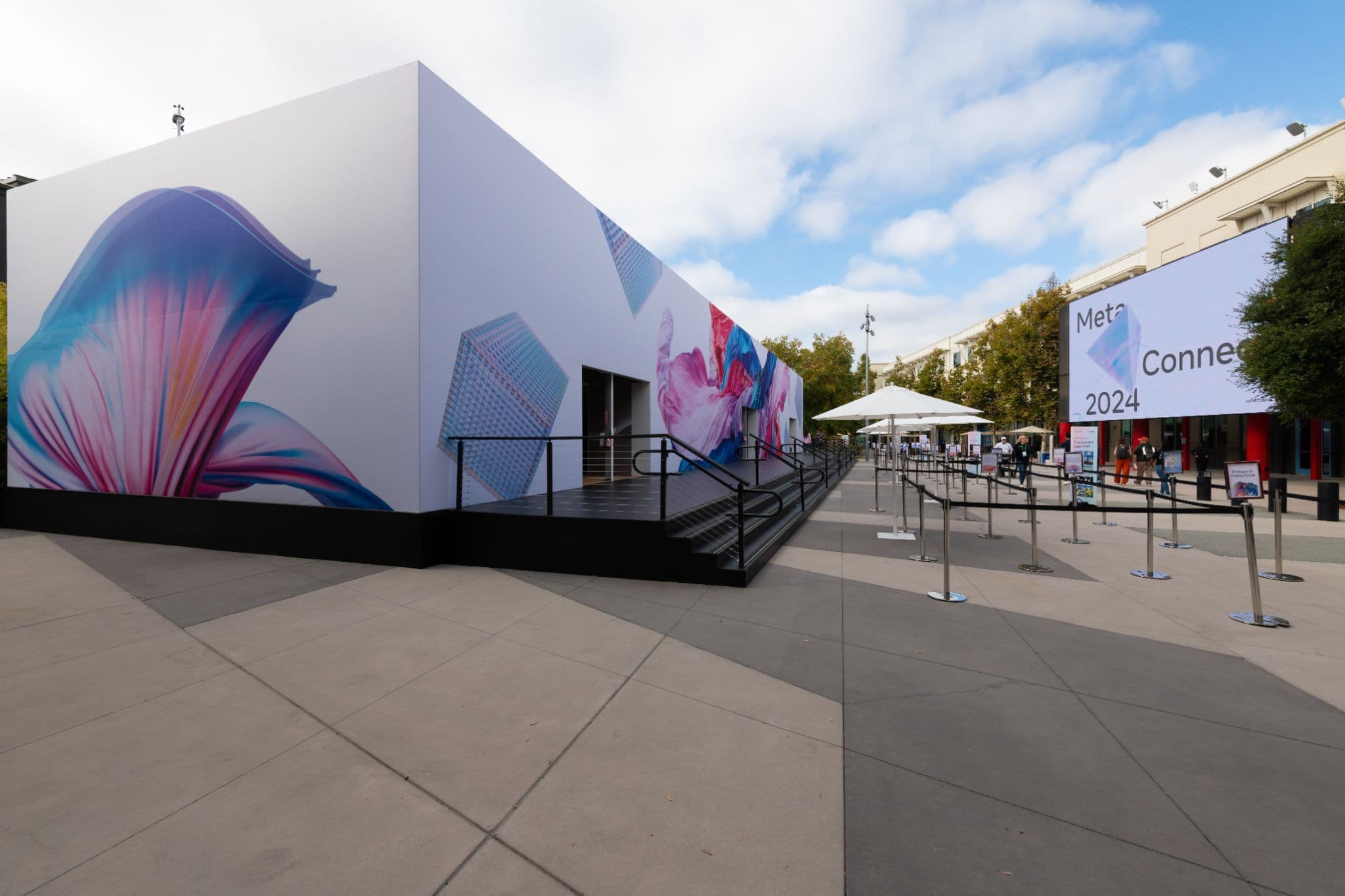 Outdoor pavilion exterior with an abstract mural and a Meta Connect banner in the distance.