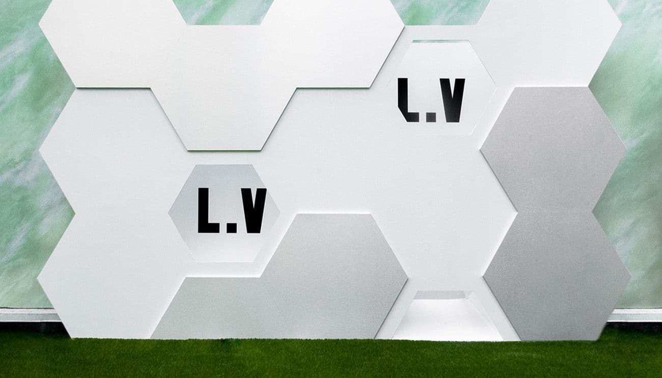 White hexagonal wall panels with LV lettering set against a mint green backdrop.