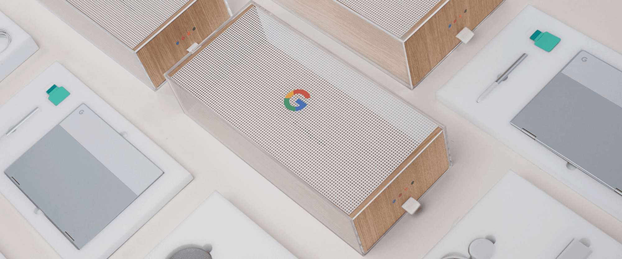 Overhead view of multiple wood-and-acrylic packaging boxes with perforated lids and a Google logo, surrounded by open trays holding devices.