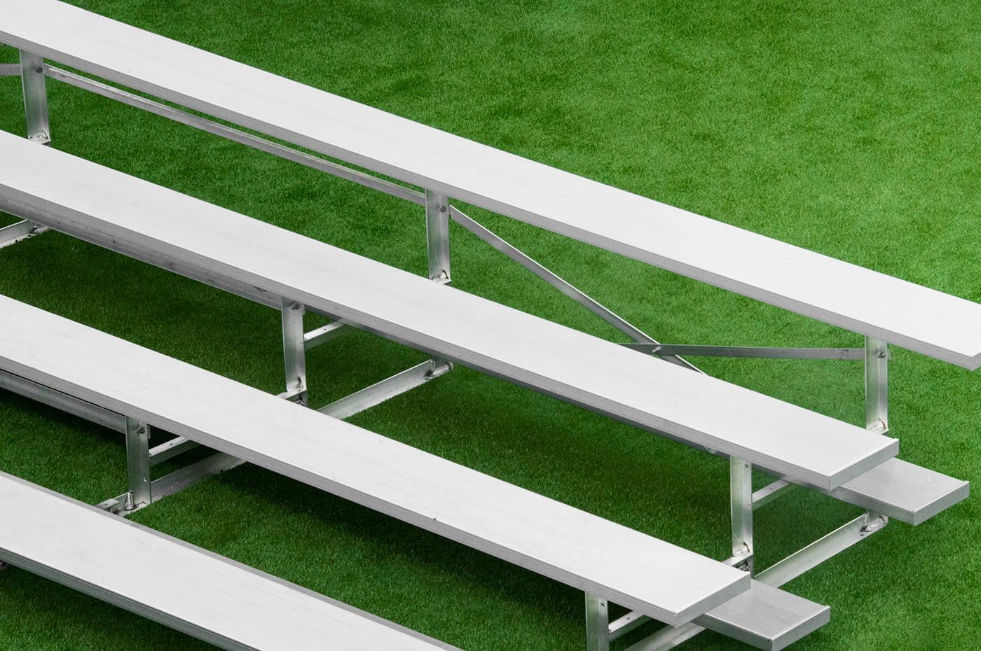 Rows of aluminum spectator bleacher seating on artificial turf.