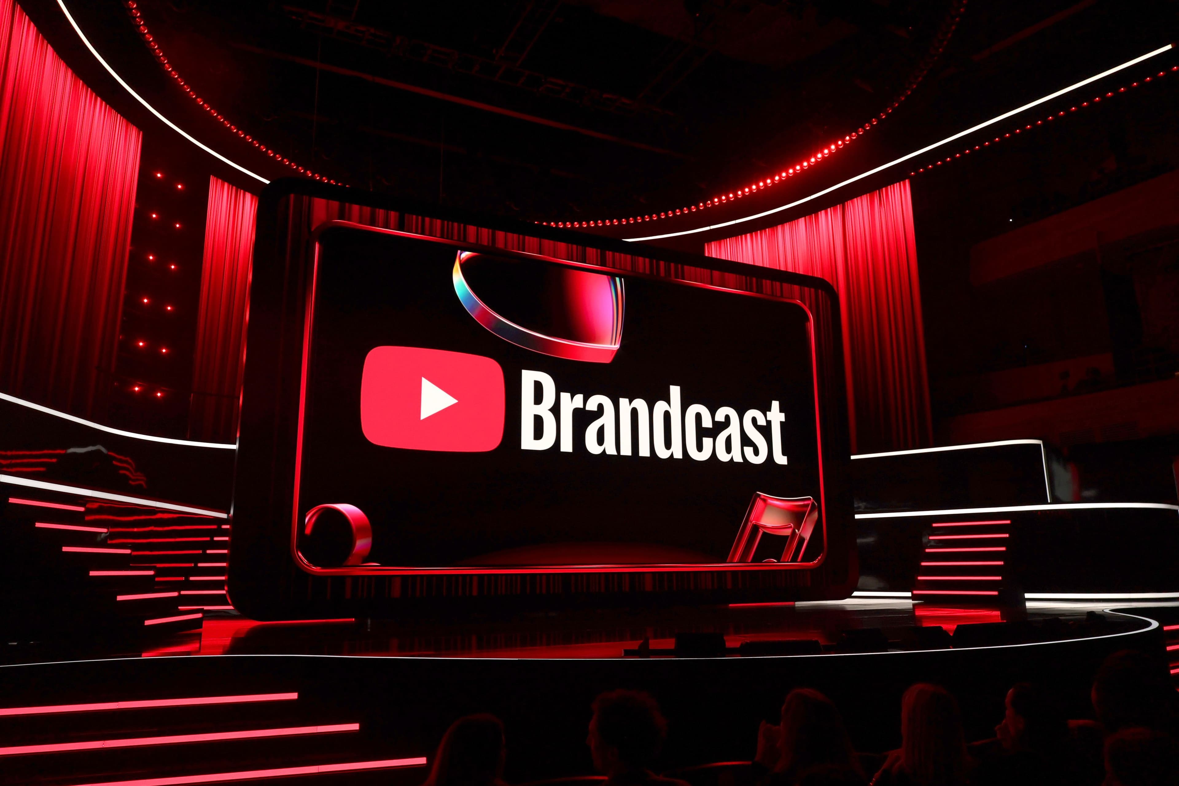 Circular red YouTube Brandcast logo screen glowing above a red-lit staircase stage