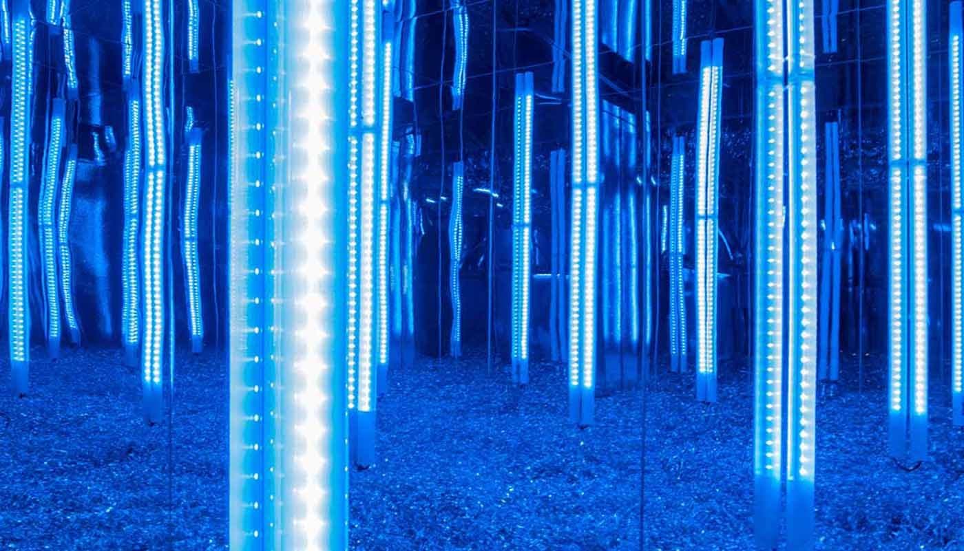 Mirrored room lined with vertical blue LED light tubes reflected infinitely.