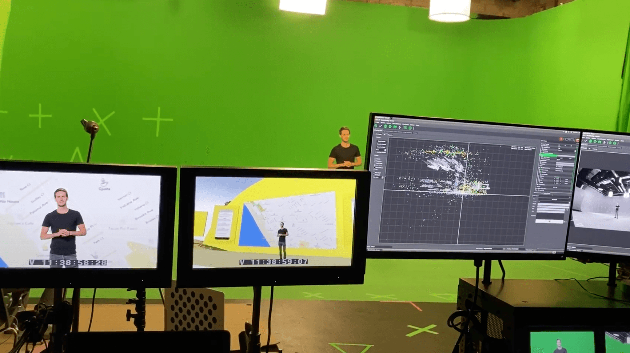 Behind-the-scenes view of a green-screen production set with monitors and a presenter.