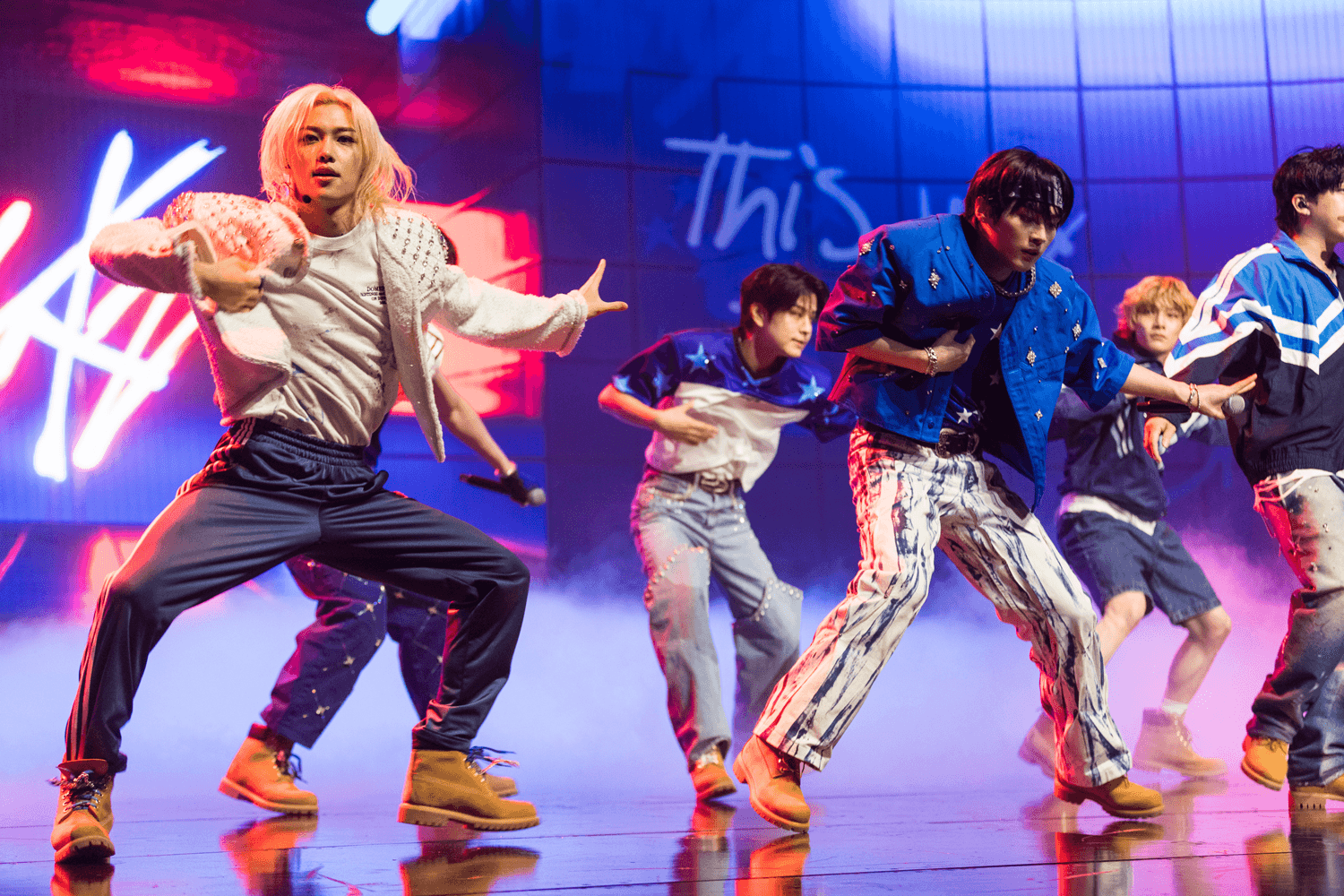 Group of dancers performing in front of a screen with graffiti-style text graphics