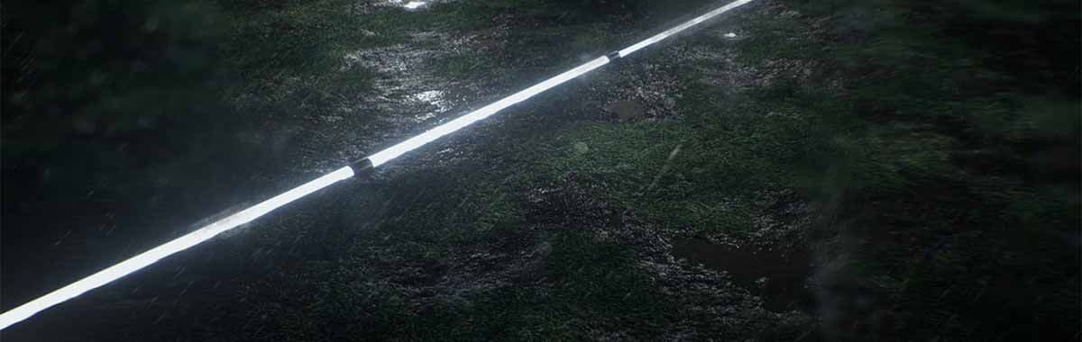 A single bright light beam streaking across a dark grass field at night