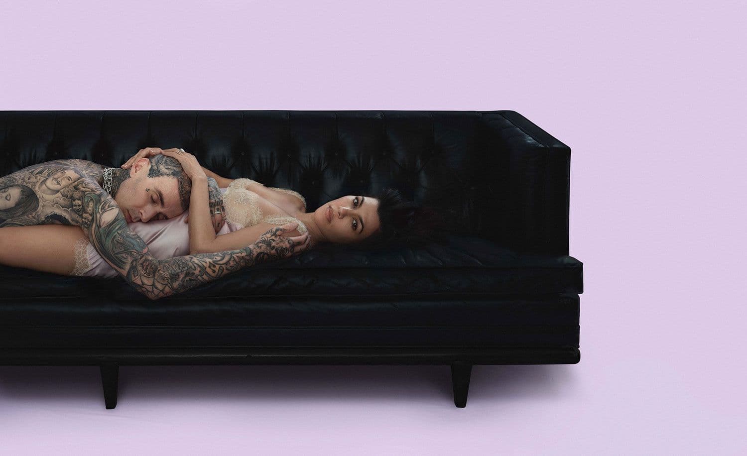 Woman reclining on a black tufted leather sofa.