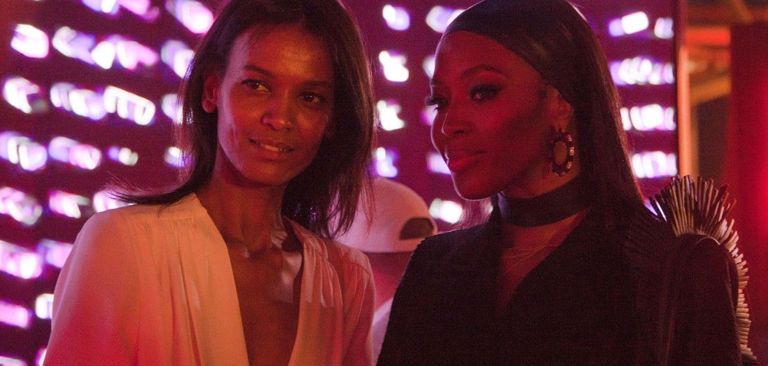 Two women smiling together at an event with a pink-lit backdrop.