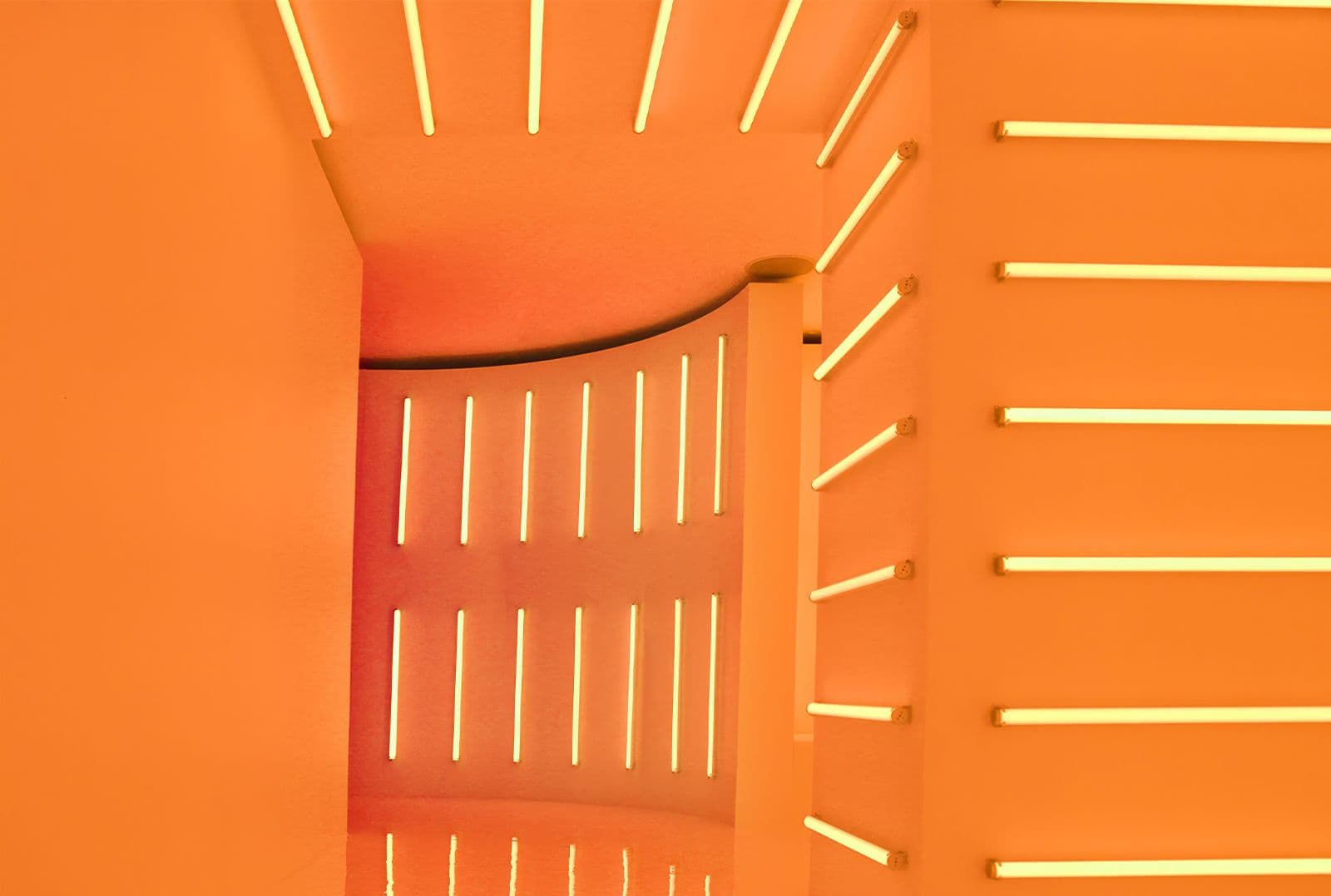 Warm orange room with a curved wall lined in horizontal amber neon strips.