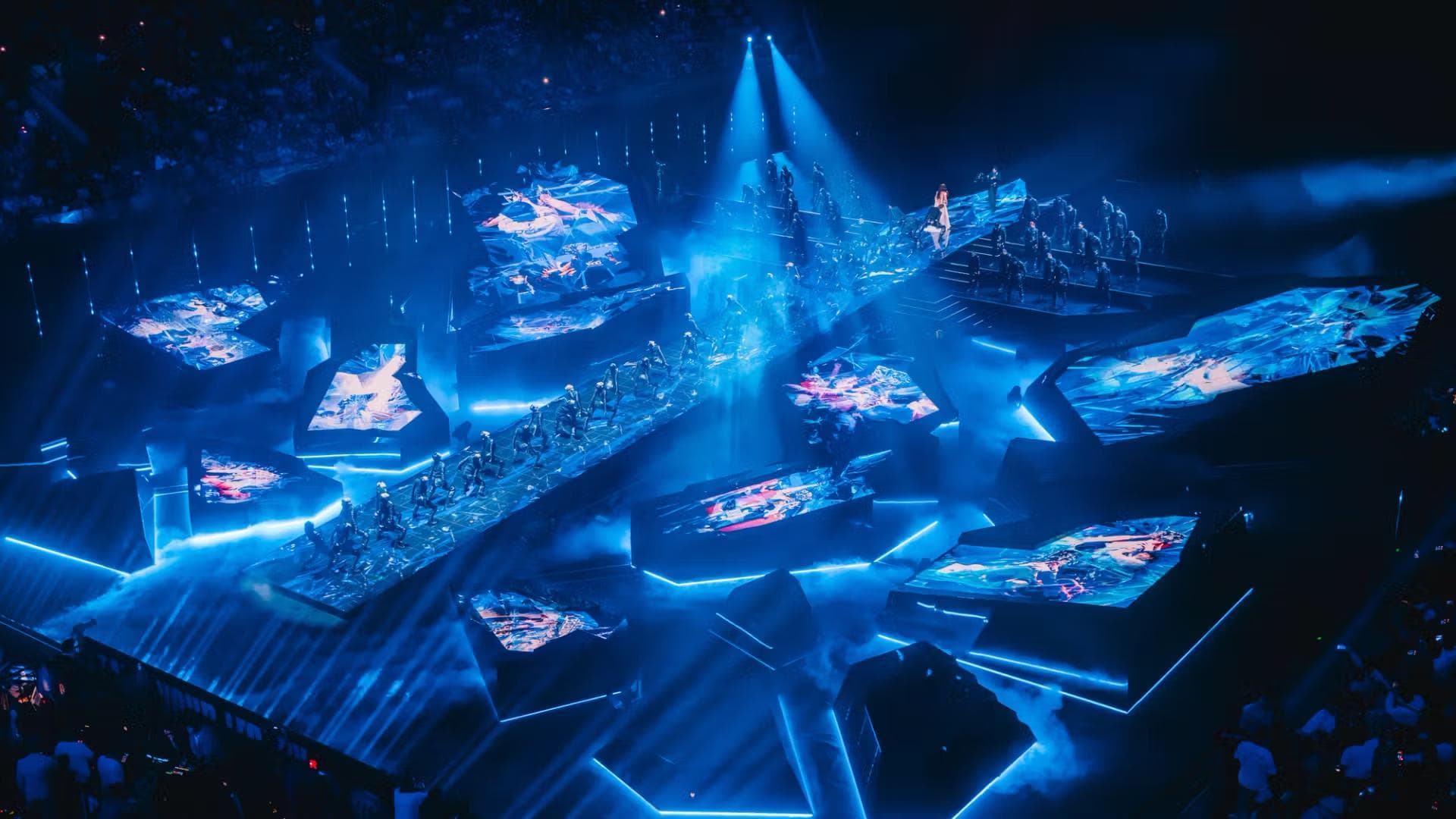 Glowing blue holographic stage set piece resembling a faceted crystal, viewed from above with radiating light beams.