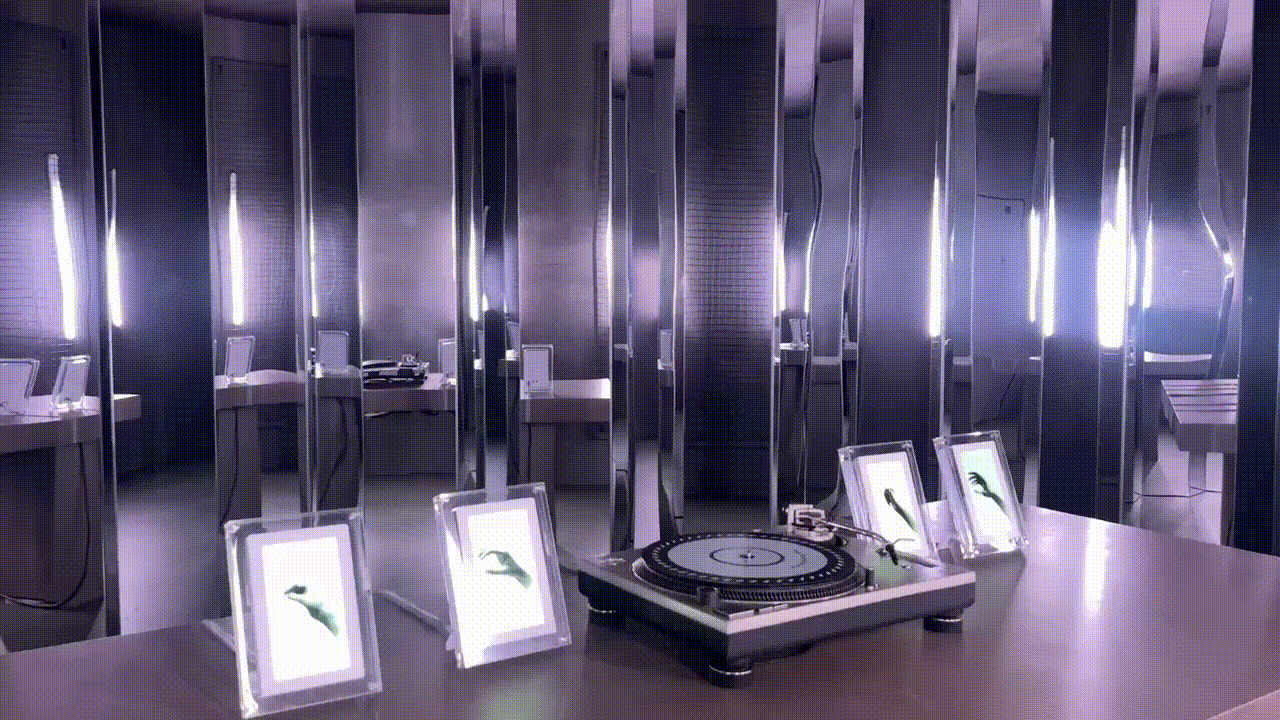 Mirrored room with framed photos on display stands and a turntable on a round table.