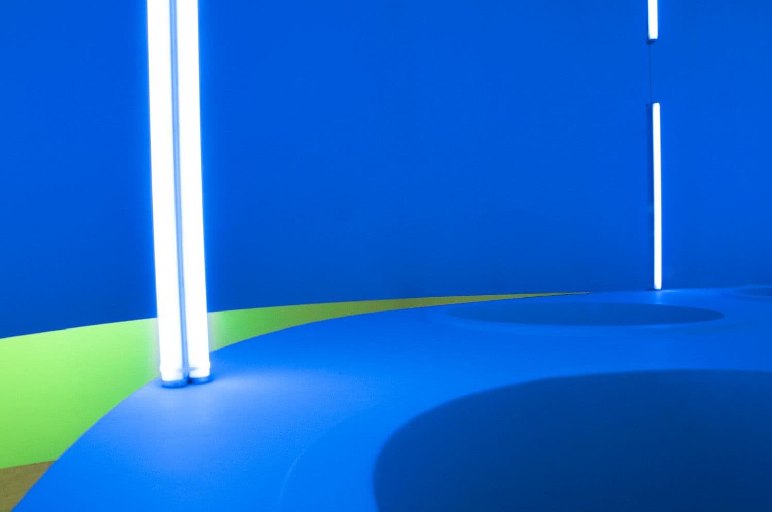 Blue curved ceiling lined with vertical white neon light tubes.