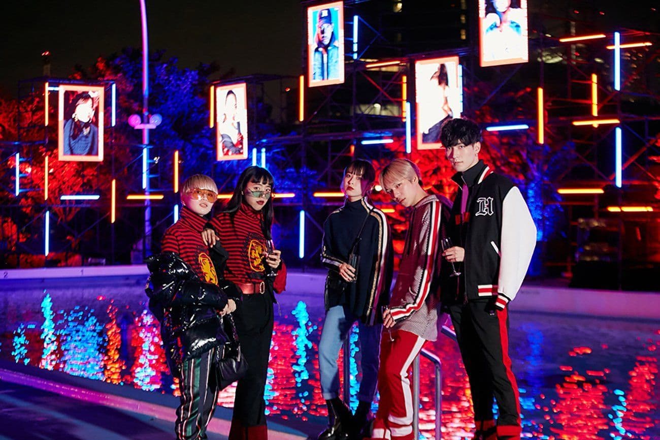 Group of five people posing together beside a reflecting pool lit with red and blue lights at night.