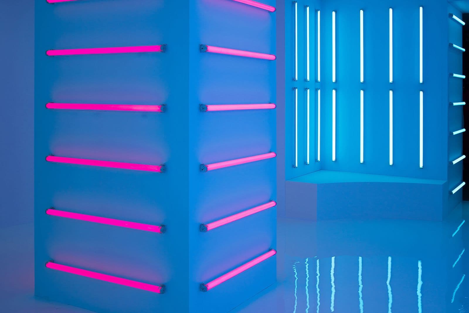 Cyan columns with and pink neon lights, blue glowing light bars reflected on the floor.