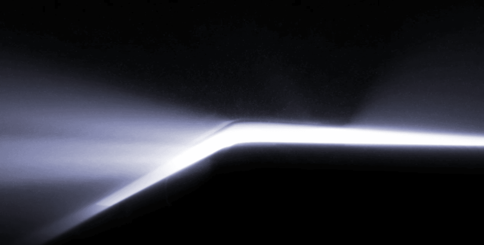 Close-up of a glowing white line running along a folding hinge edge against black.