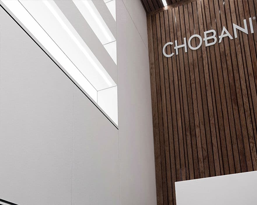 Interior corner with an angled ceiling light strip and the CHOBANI wordmark on the wall.