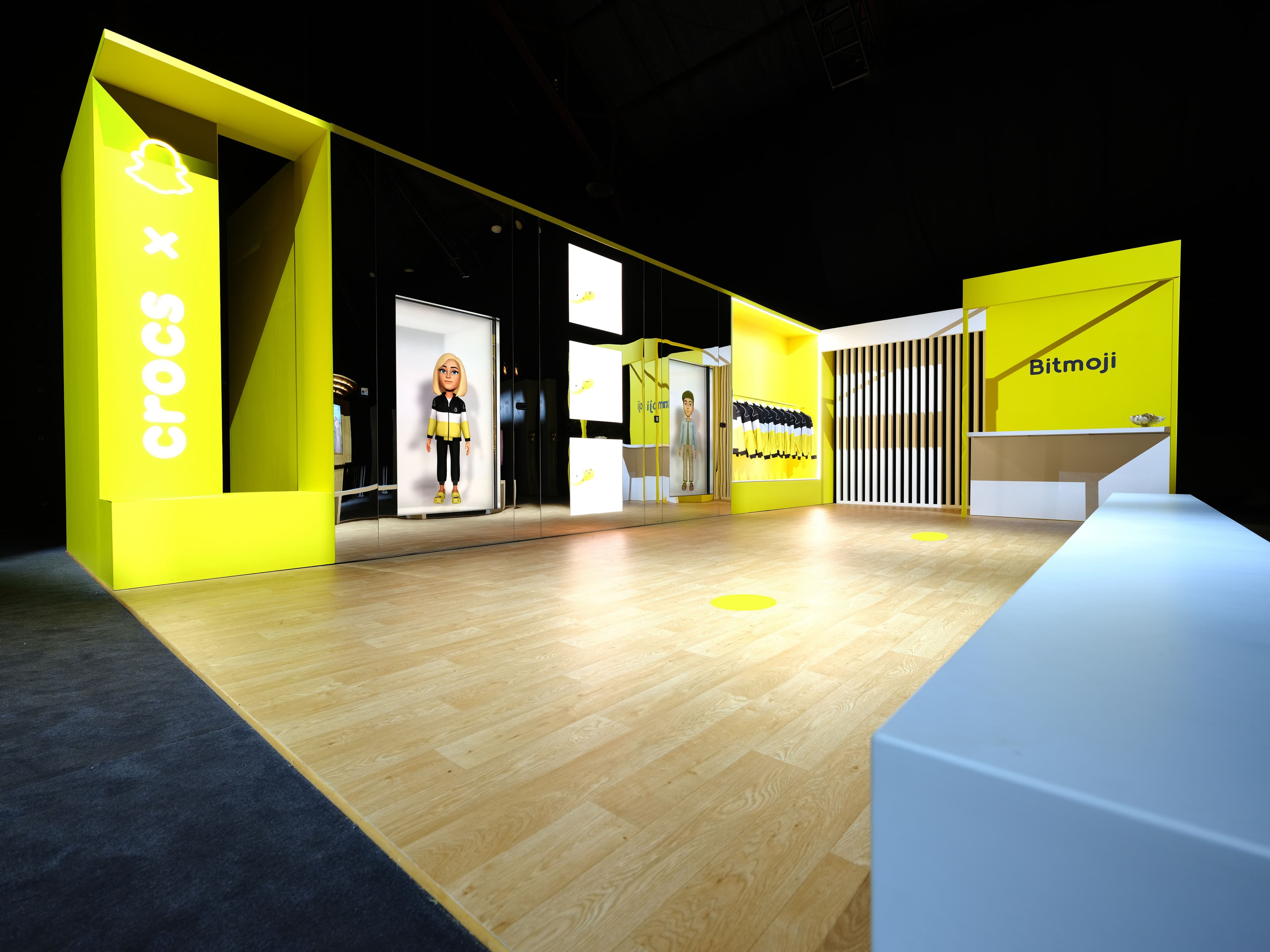 Yellow branded activation booth at night with product displays lining angled walls.