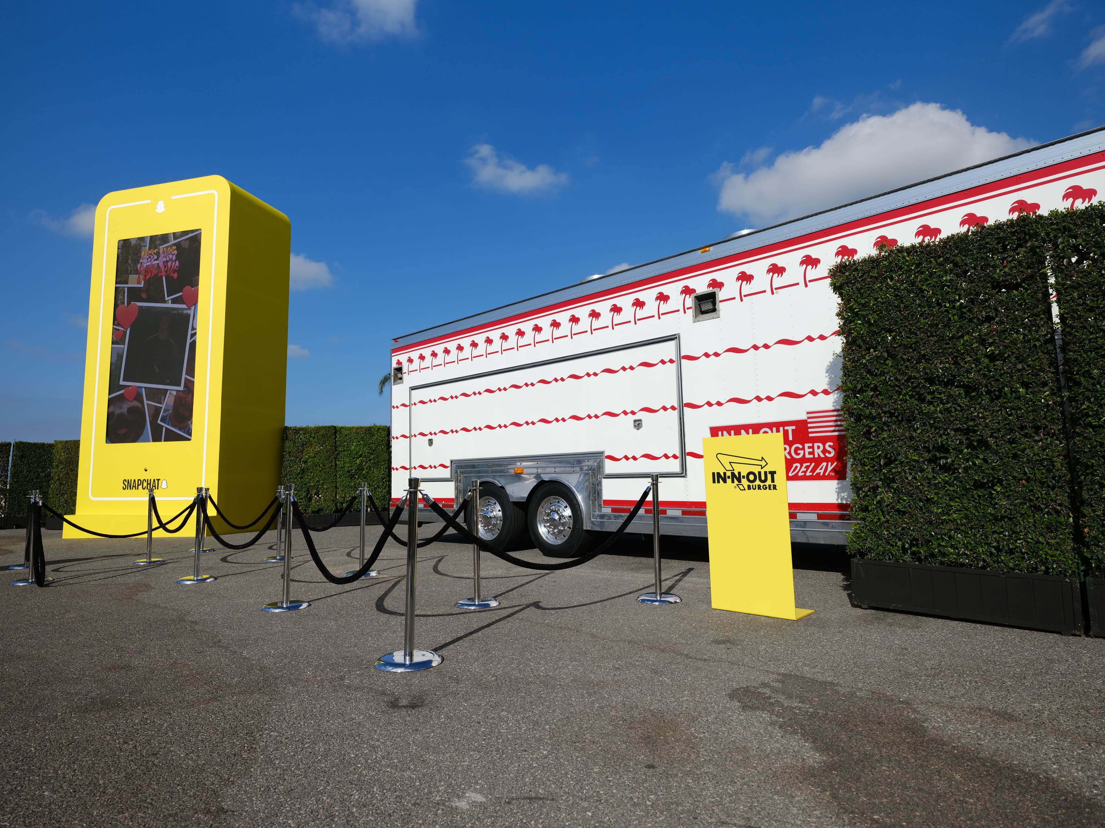 Yellow shipping-container-style structure with a roped queue line outside a striped tent.