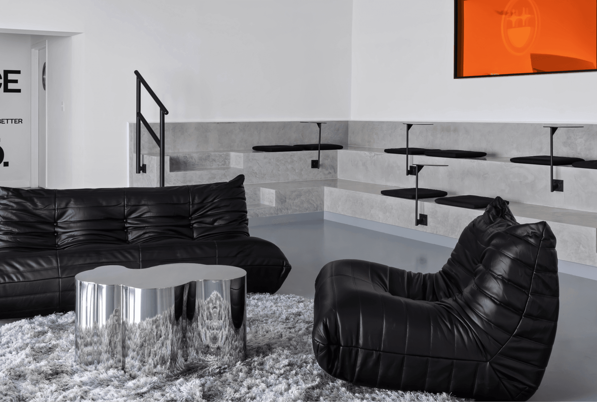 Black leather sofa and armchair with a round mirrored coffee table on a shag rug in a lounge area