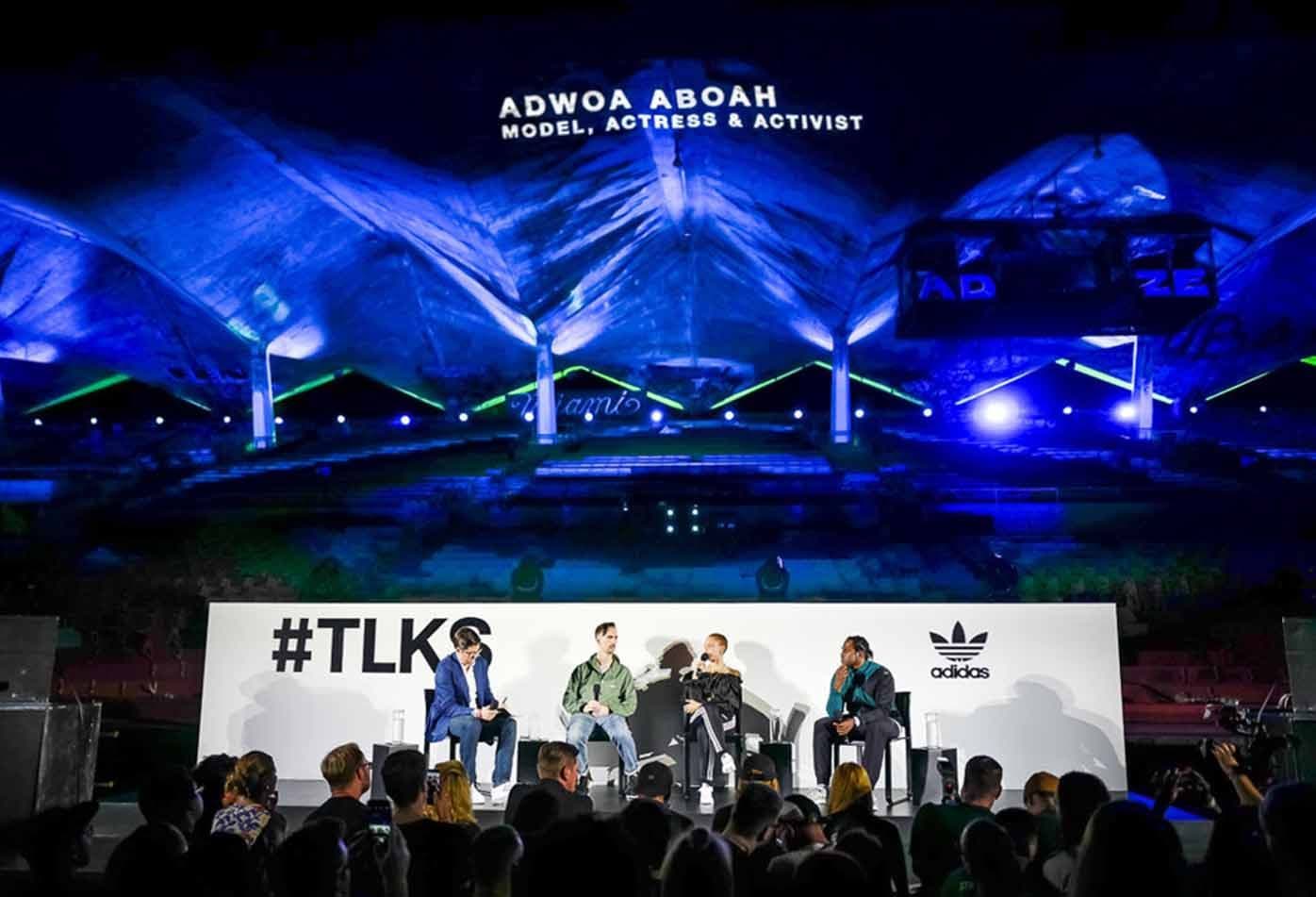 Panel discussion on an outdoor stage under a blue-lit tent structure, with "ADWOA ABOAH, MODEL, ACTRESS & ACTIVIST" projected above and a #TLKS adidas banner in front.