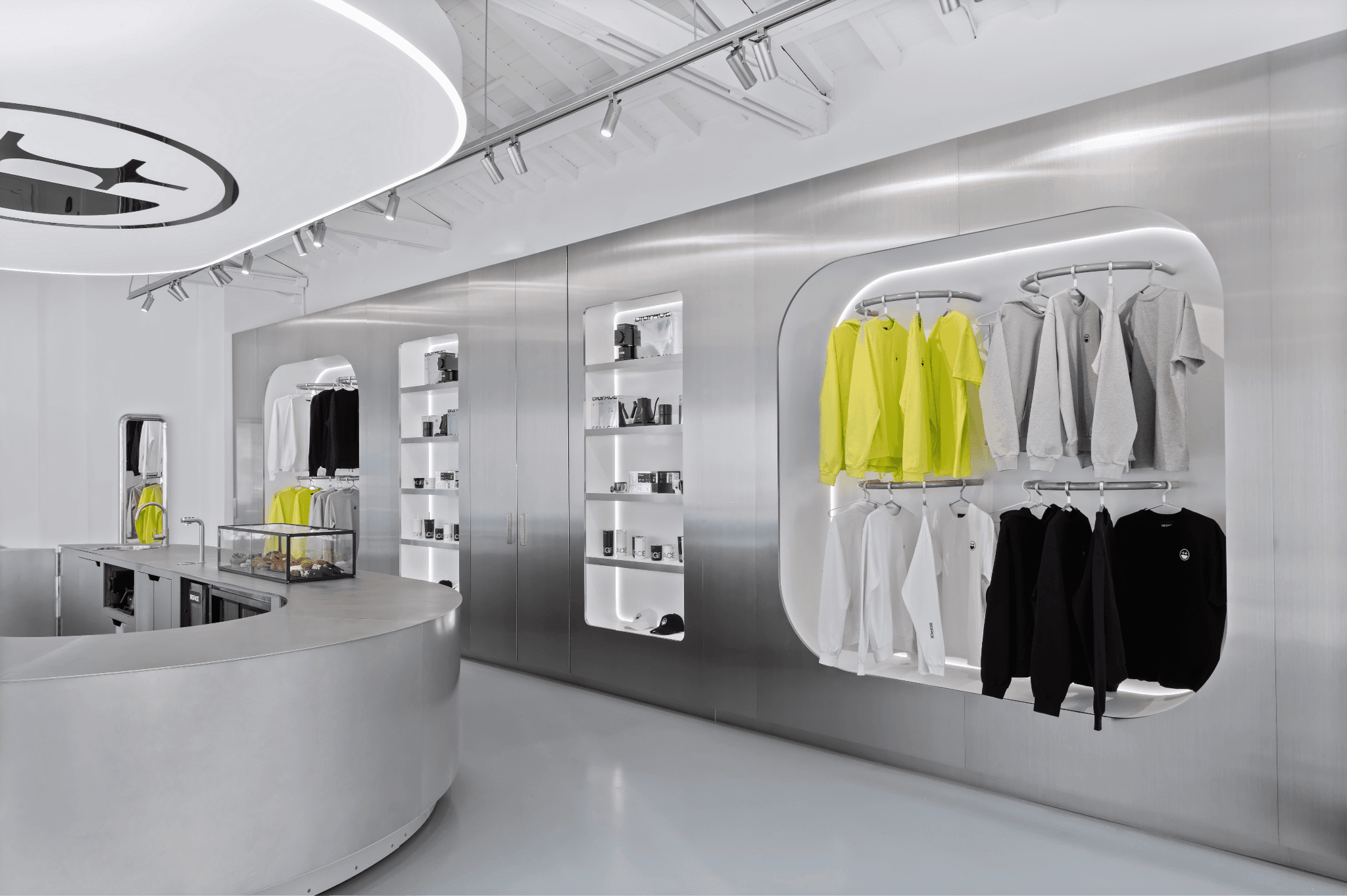 Store interior with curved metal walls, cutout display shelves, and hanging yellow and black clothing