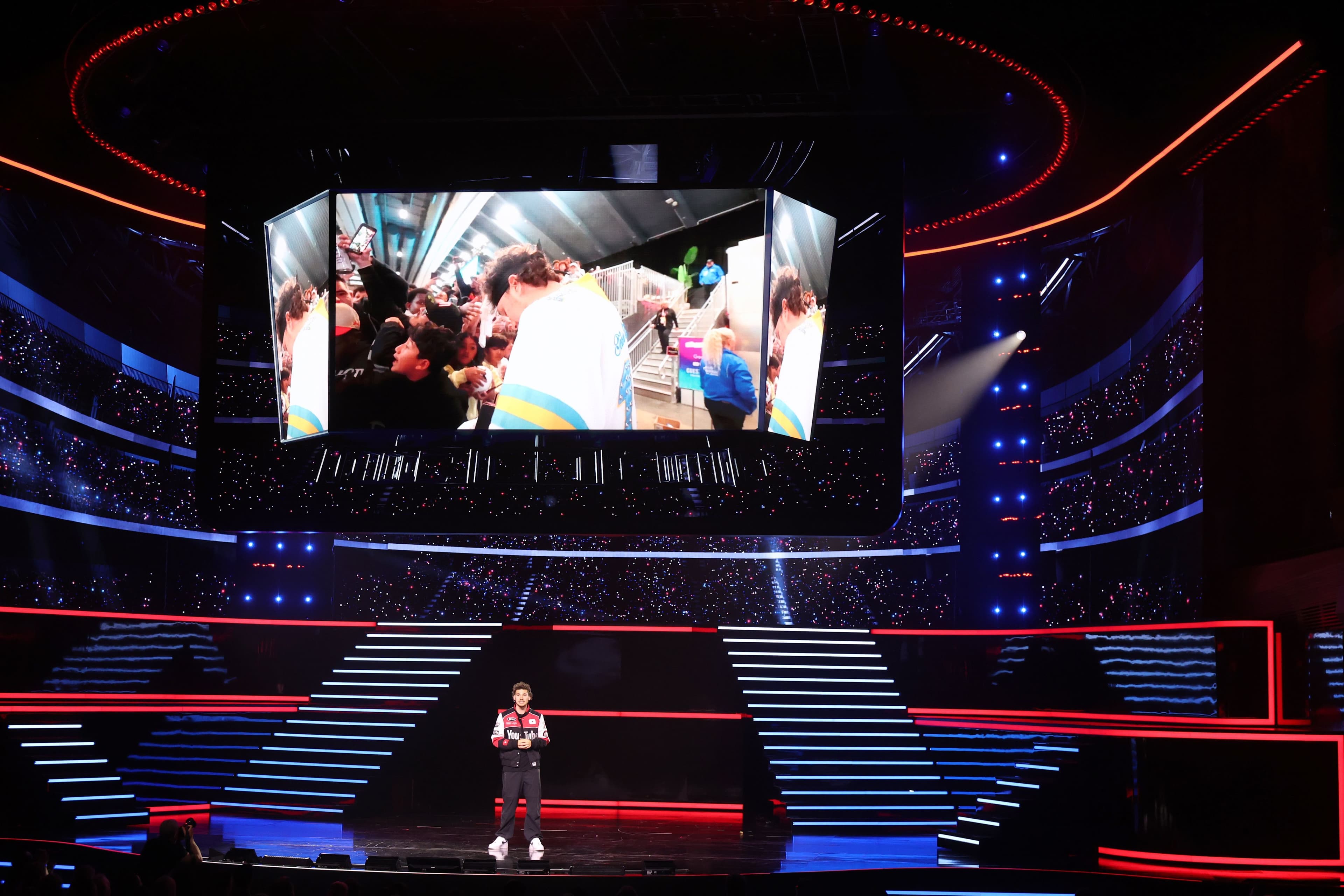 Red-lit stage screen showing a grid of photos above a red staircase