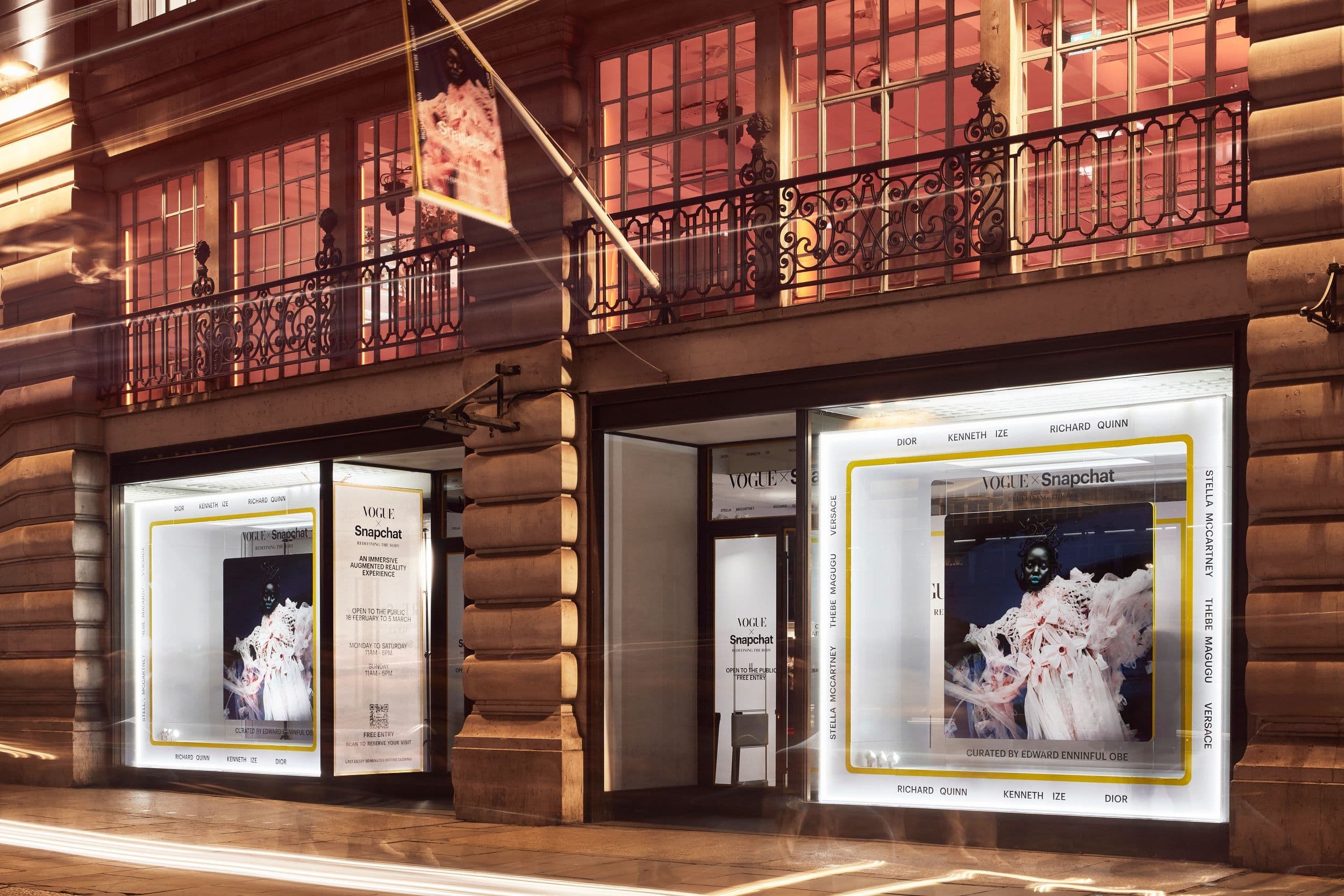 Storefront exterior at night with illuminated display windows on a brick building.