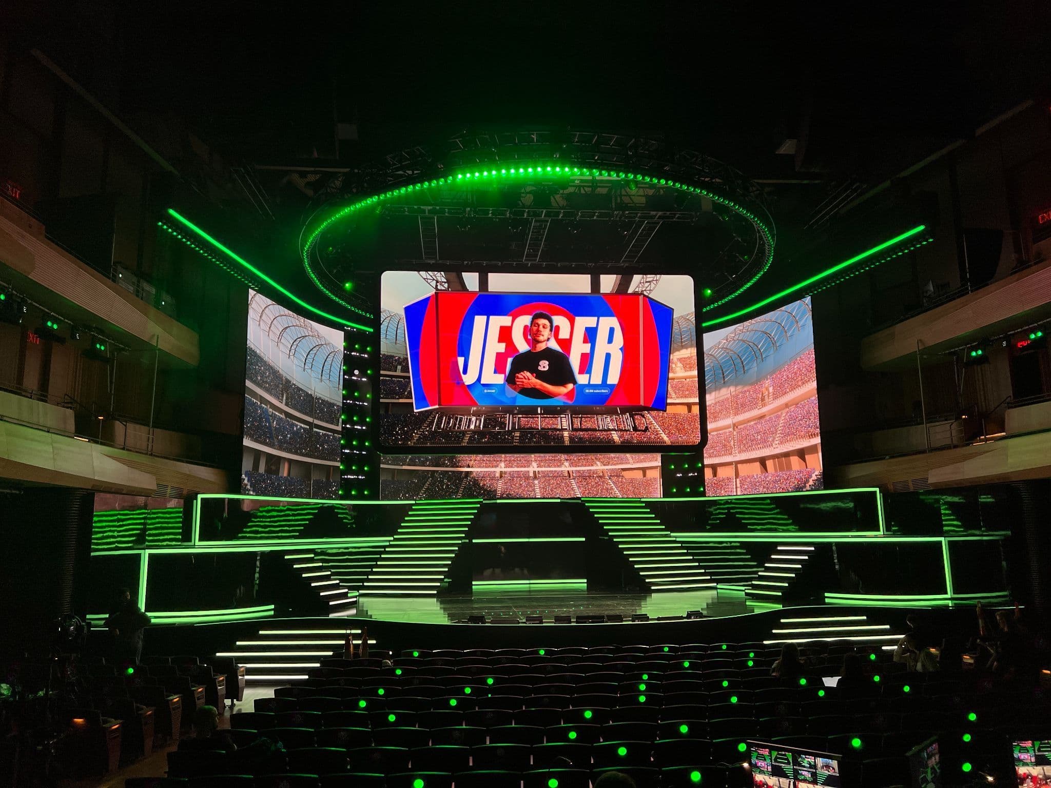 Circular stage screen with a colorful logo, ringed by green lighting