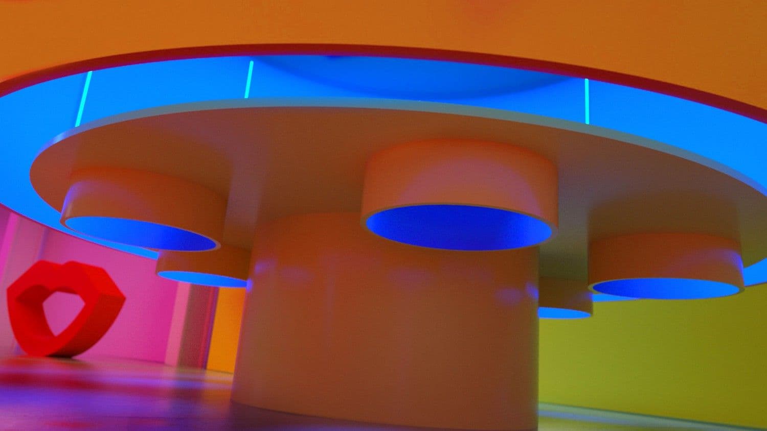 Wide shot of orange round pedestal tables under blue circular ceiling discs with a red heart-shaped sculpture.