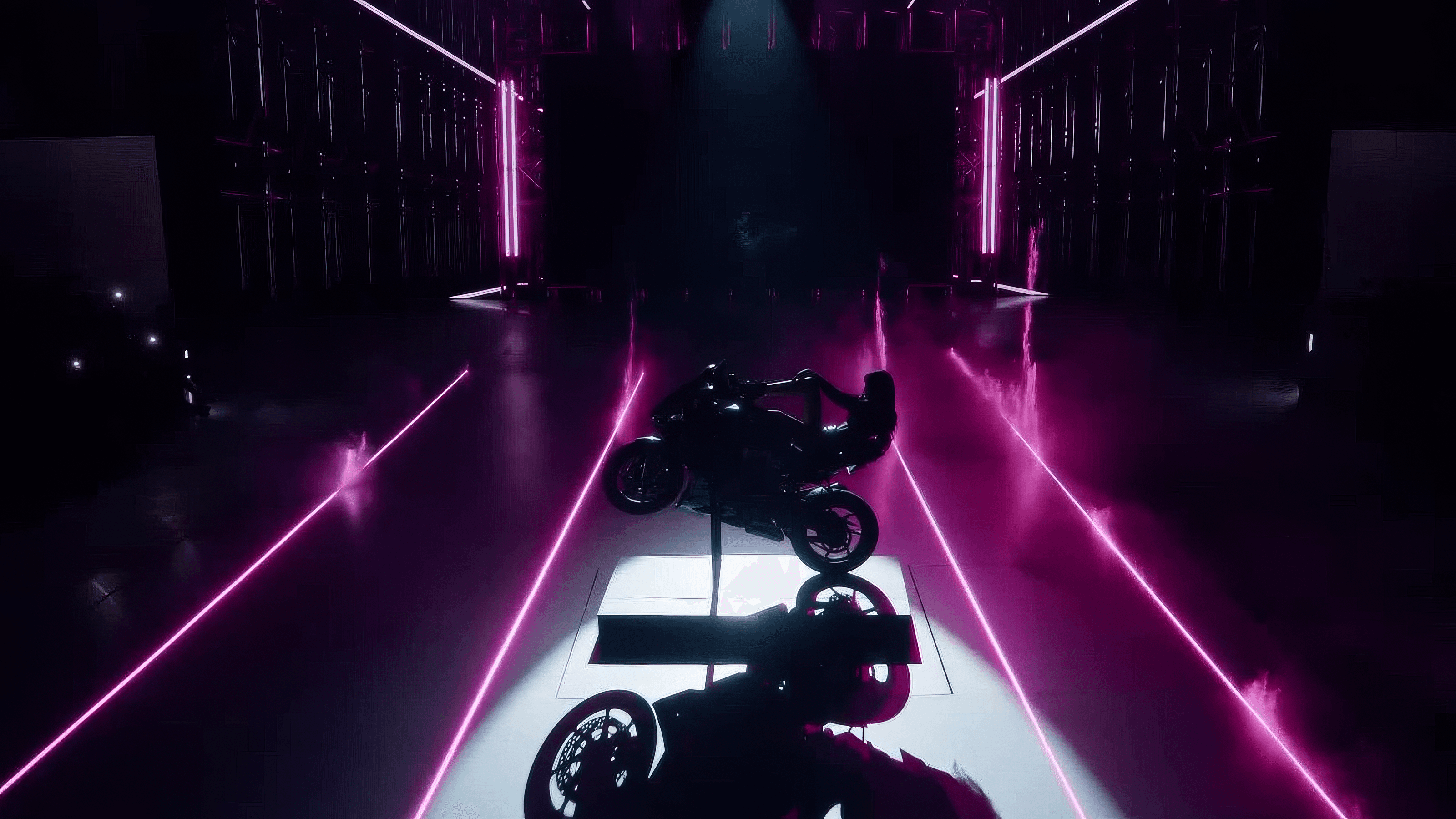 Aerial view of a motorcycle parked in a dark corridor lined with pink and purple neon laser beams.